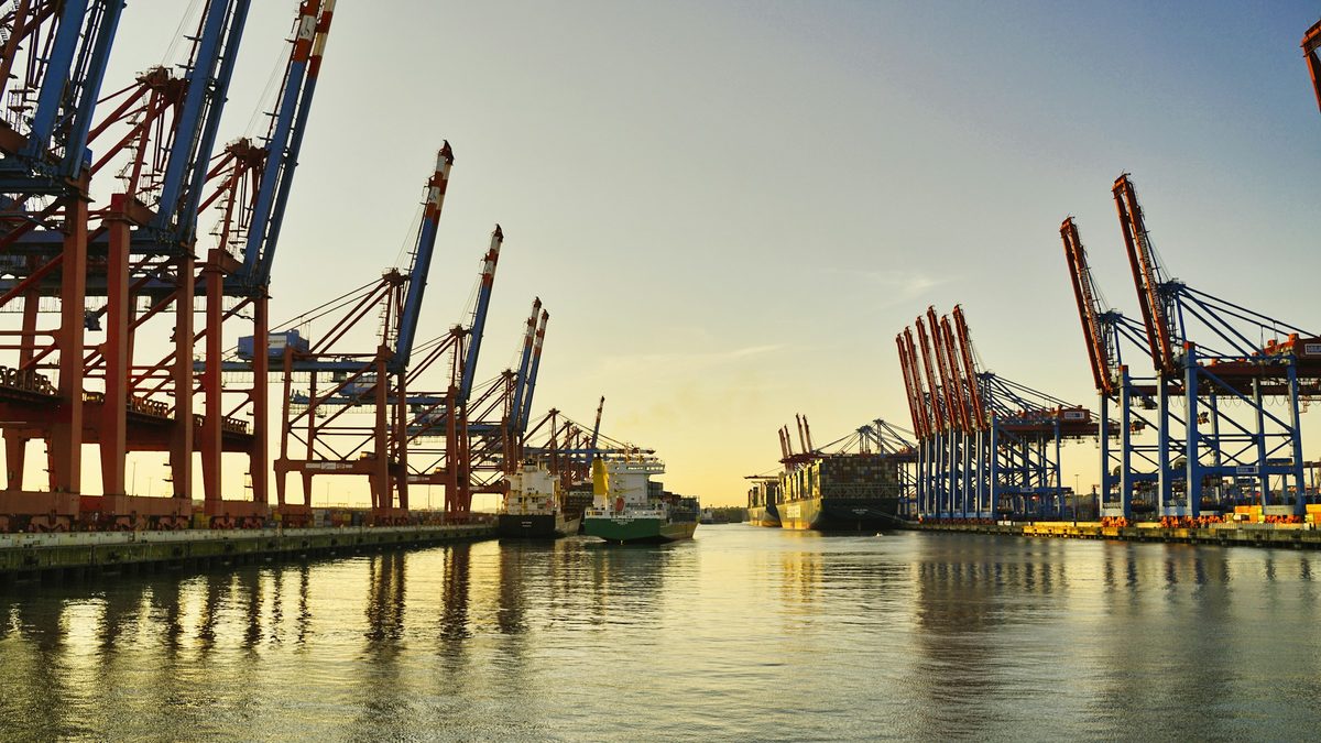 Container cranes at a busy sea port at sunset